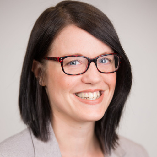 Professional woman with brown shoulder length hair, glasses and a bright smile.