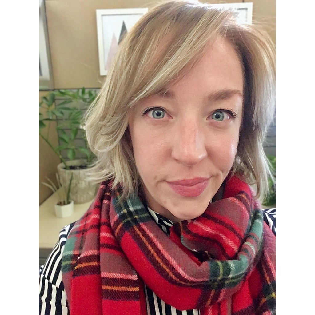 Woman with blonde hair, blue eyes, and wearing a red plaid scarf