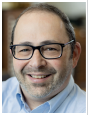 headshot of a gentleman with short dark hair & black framed glasses and wearing a blue button down shirt..  