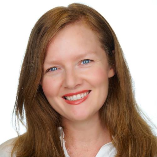 Smiling woman with red hair, blue eyes.