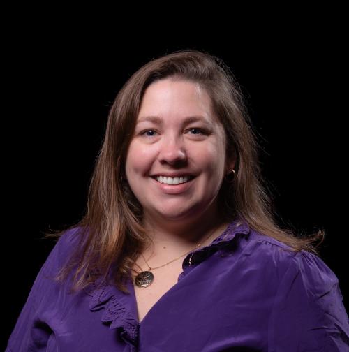 Smiling portrait of Sam Green shows her with brunette shoulder length hair in a deep purple blouse.